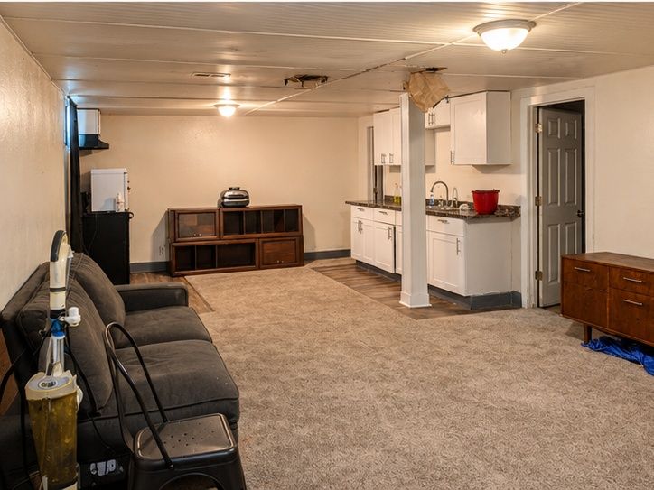 Basement living area and kitchenette, with visible ceiling damage